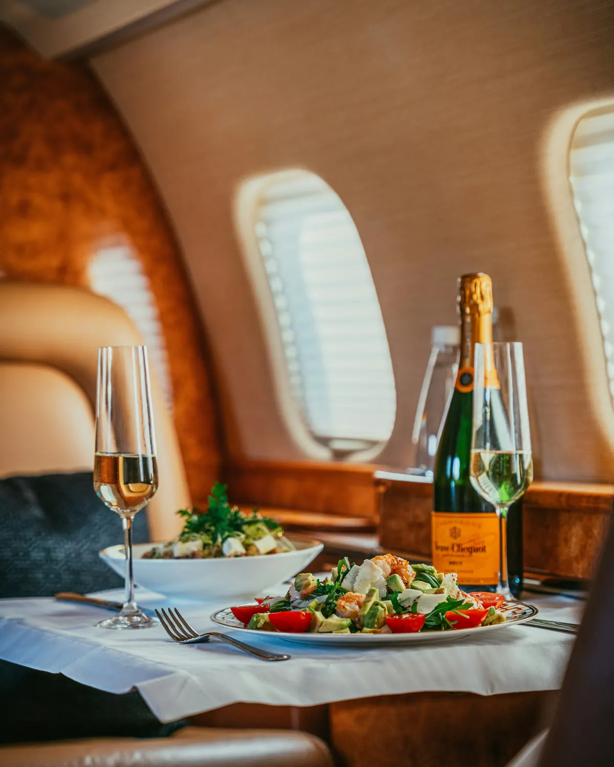 Champagne and a plated salad on a table beside a cabin window