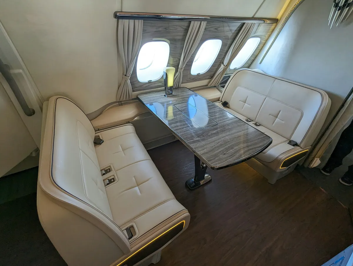 Club table between two cream leather sofas in a wide jet cabin