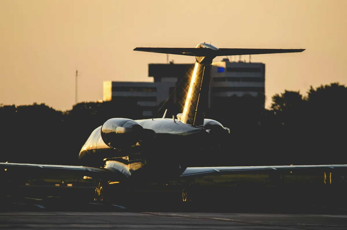 Business jet on the apron at dusk, its tail catching the last of the light