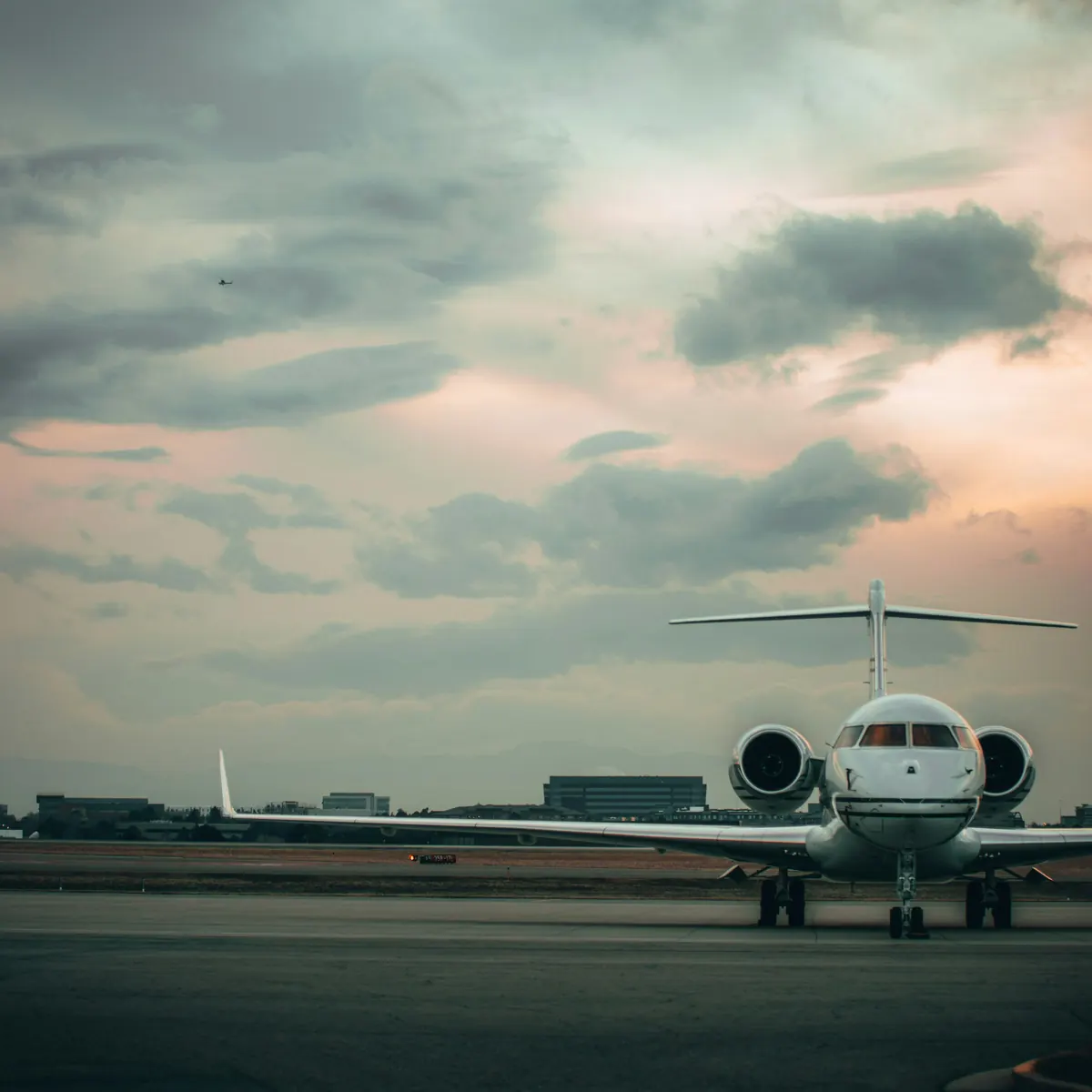 Long-range business jet facing the camera on an apron under a dusk sky
