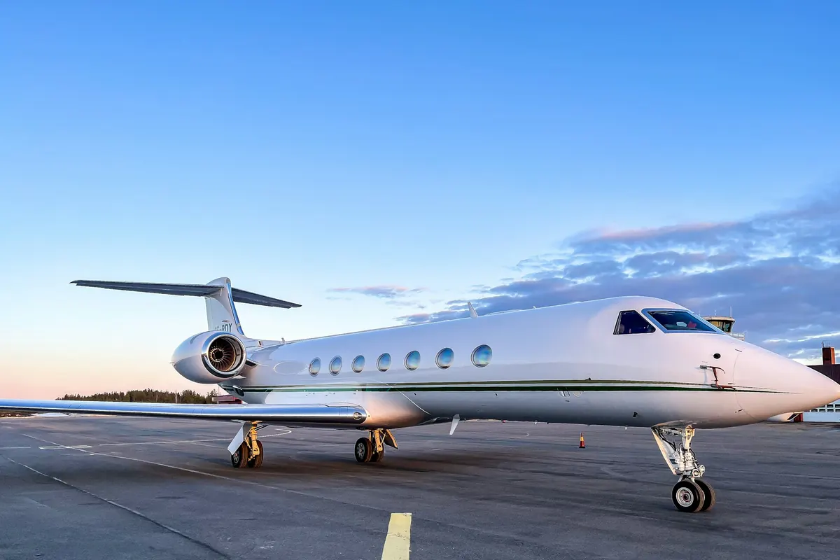 Large business jet on a sunlit apron under a clear blue sky