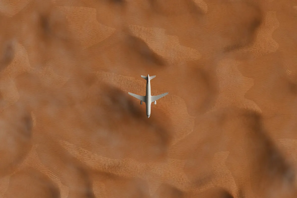 Business jet crossing rippled desert dunes, seen from directly above
