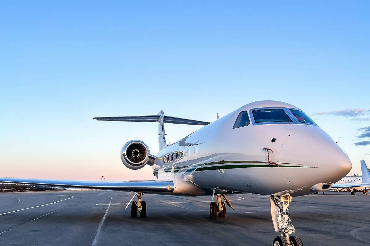 Large business jet on a sunlit ramp, seen from the front quarter