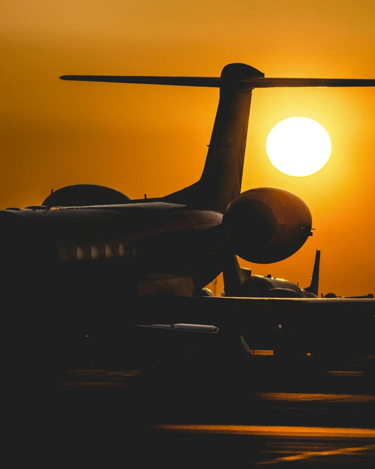 Silhouette of a long-range business jet against a low orange sun