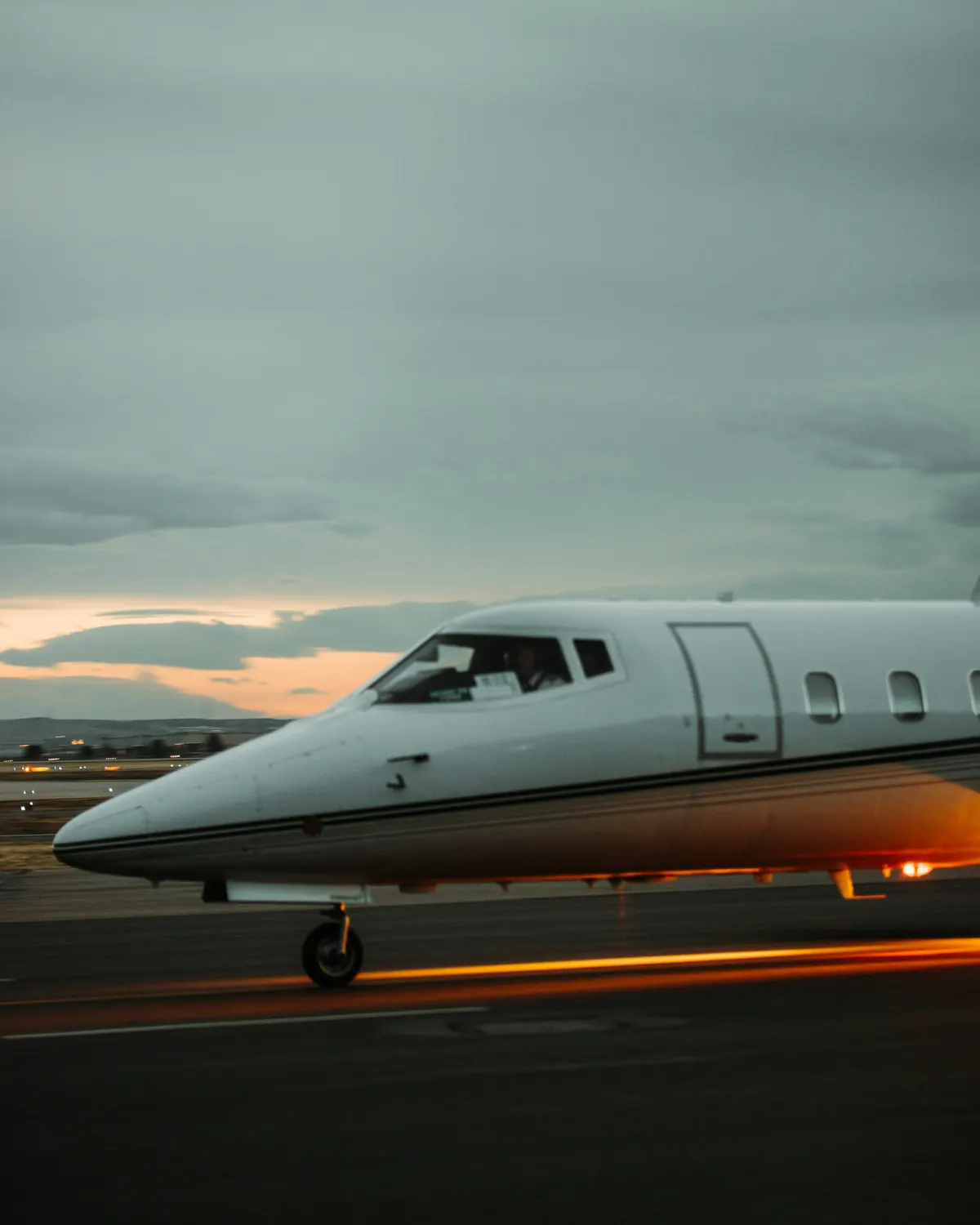 Nose and cockpit windows of a business jet on the apron at dusk